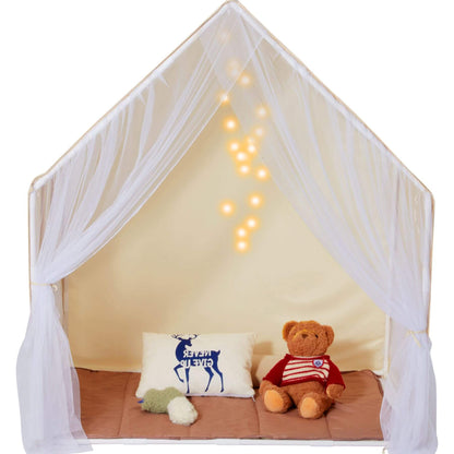 Children's playhouse with a teddy bear and pillow inside, decorated with fairy lights.