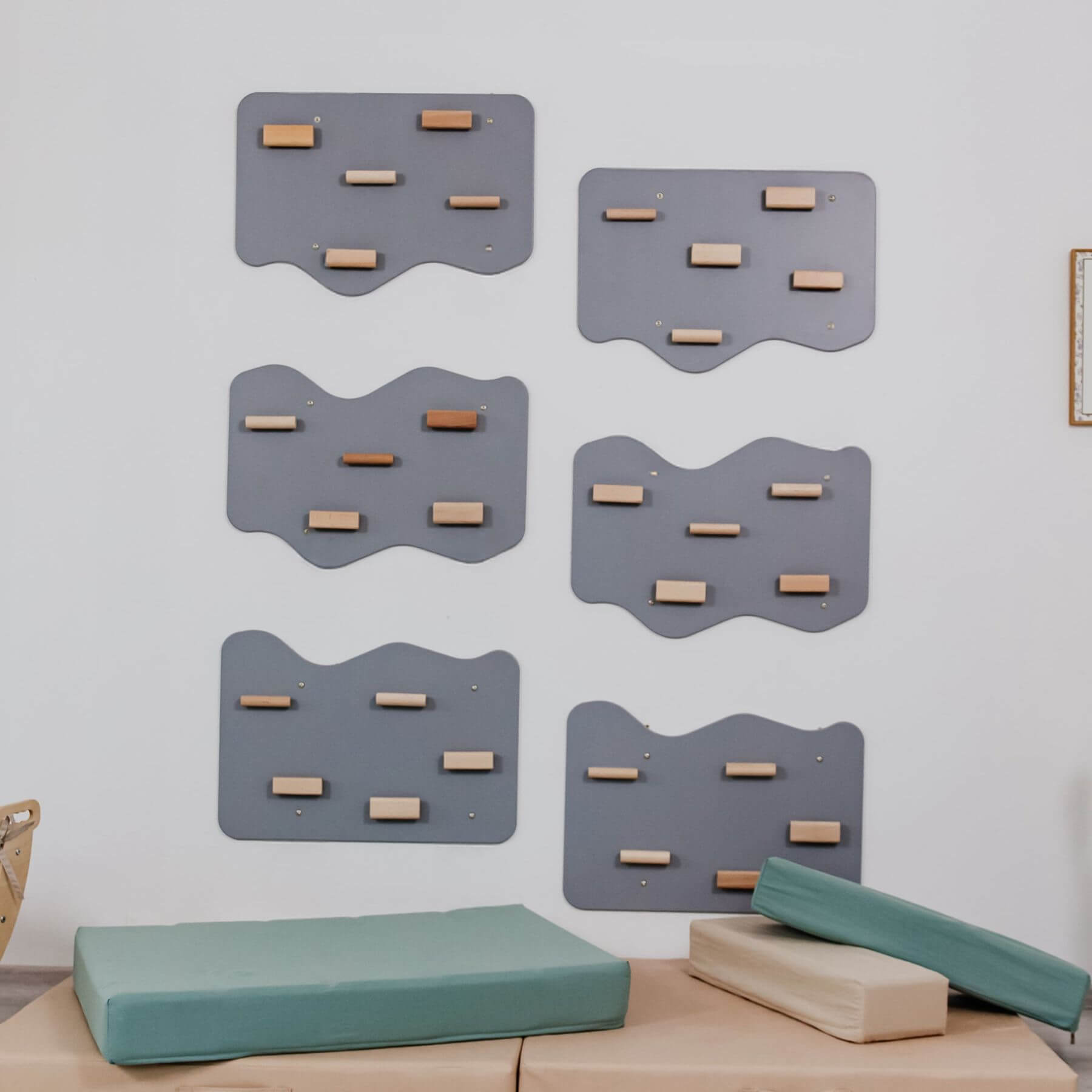 Set of gray wall climbing structures with wooden steps on a light gray wall.