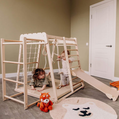 Children playing on Wood and Hearts Jungle Gym Playset with a teddy bear in a room.