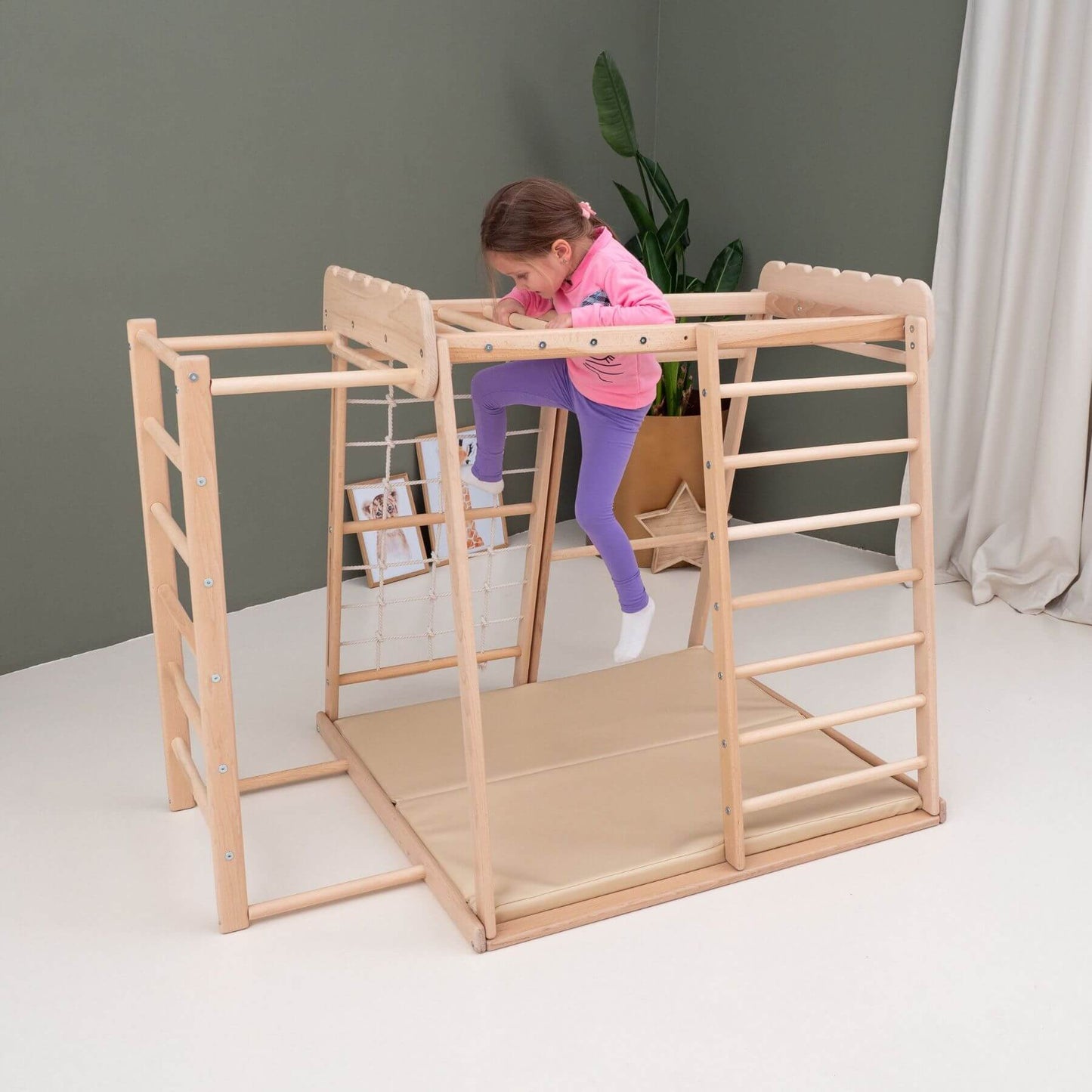 Child playing on Wood and Hearts Jungle Gym Playset in a room with a gray wall and white floor.