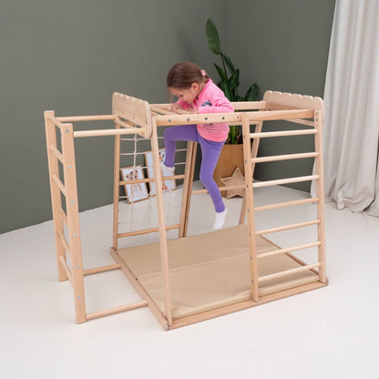 Child playing on Wood and Hearts Jungle Gym Playset in a room with a gray wall and white floor.