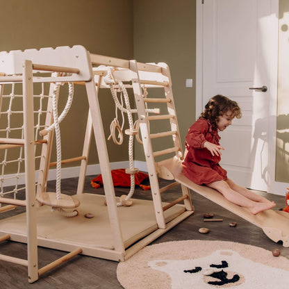 Child playing on Wood and Hearts Jungle Gym Playset in a room with a rug and toys.