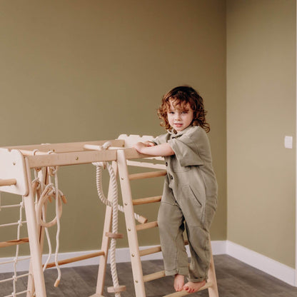 Child playing on Wood and Hearts Jungle Gym Playset against a plain wall.