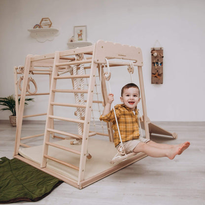 Child playing on Wood and Hearts Jungle Gym Playset in a room with white walls and a plant.