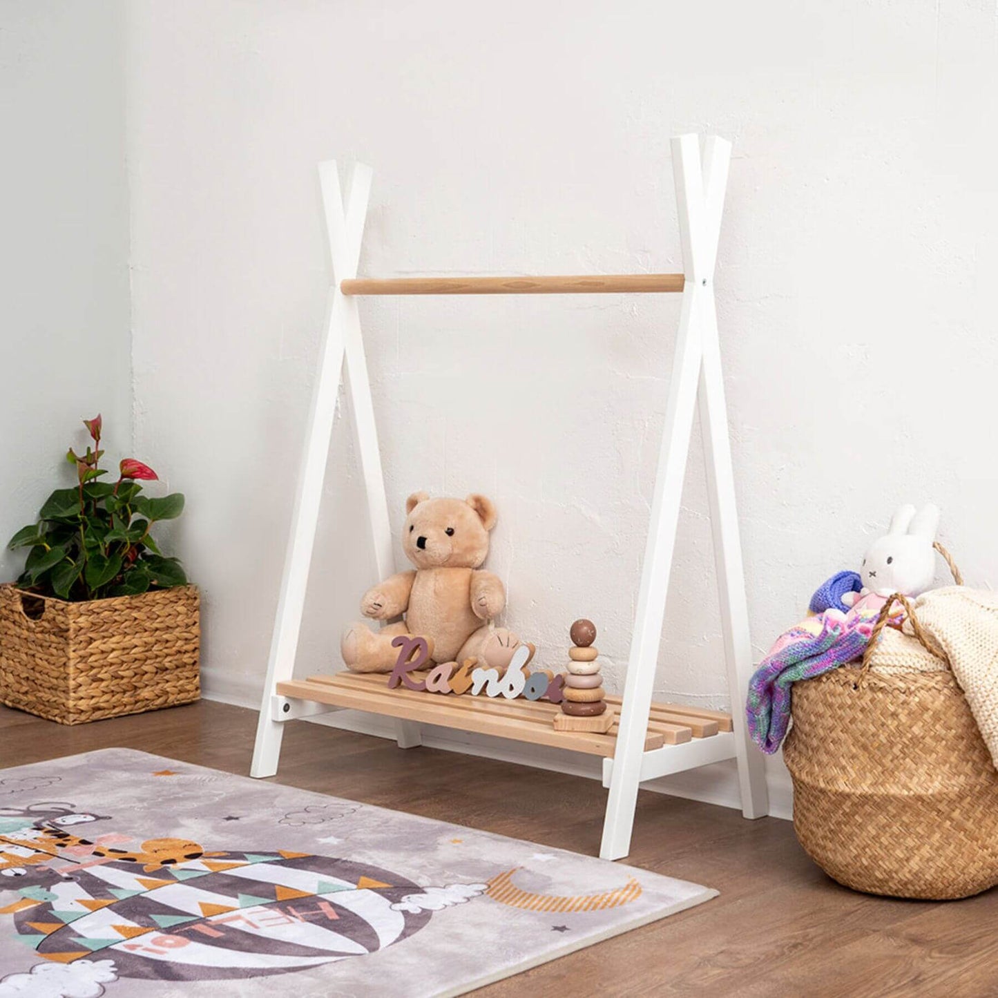 Children's playroom with Wood and Hearts Toddler's Clothes Rack, teddy bear, and toys on a white wall background.