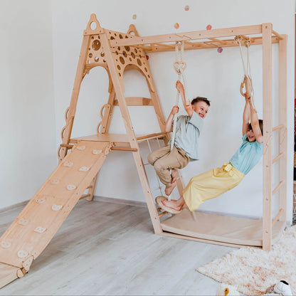 Two children playing on Wood and Hearts Wooden Playground indoors.