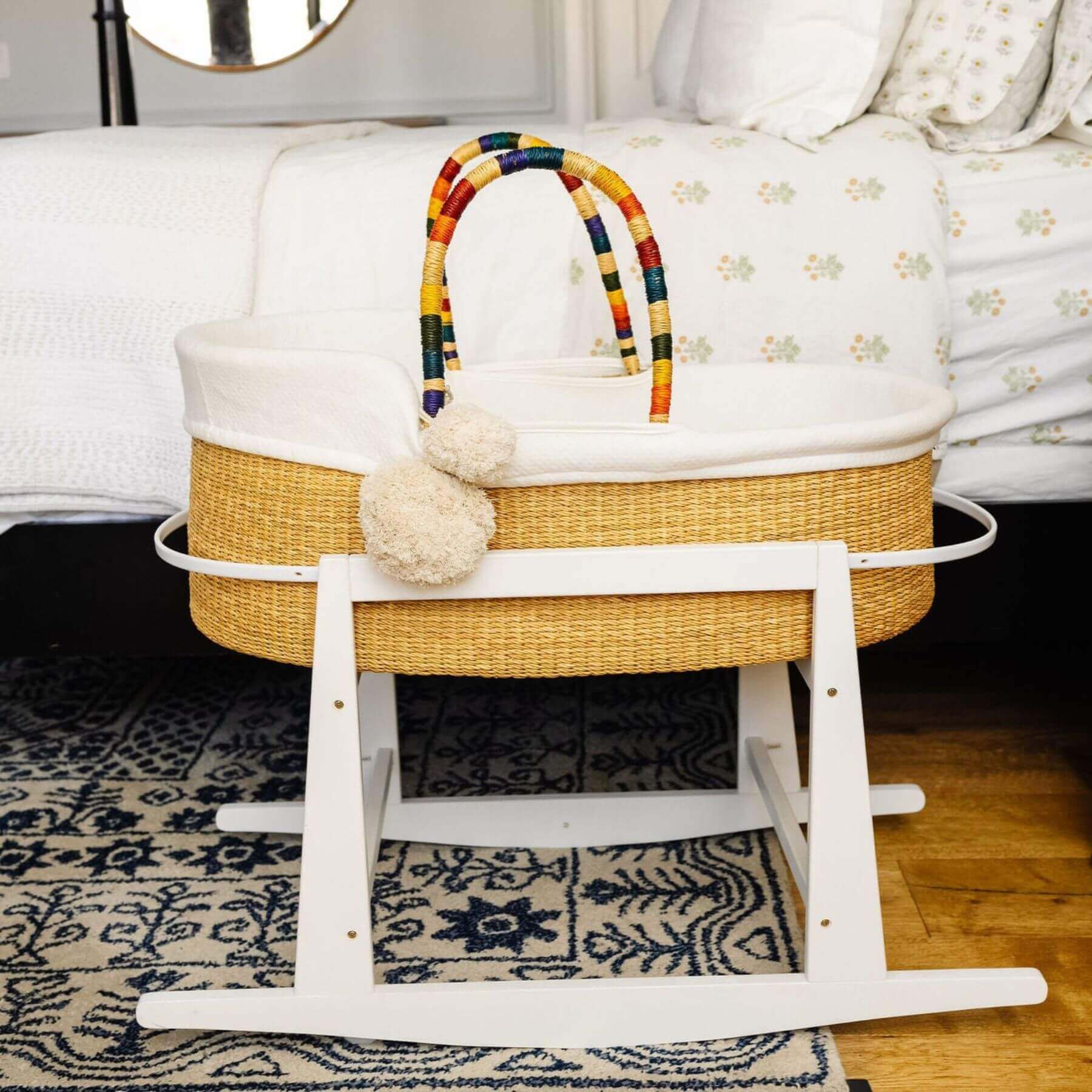 Plum+Sparrow African Moses Basket Rainbow Vegan Handle on a wooden stand in a nursery setting.