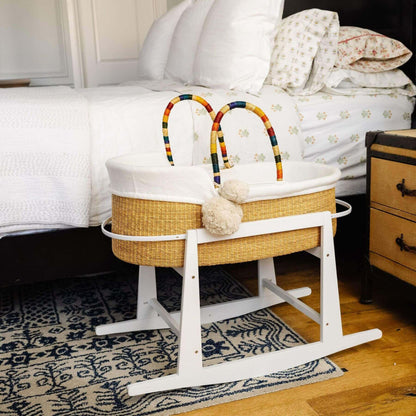 Plum+Sparrow African Moses Basket Rainbow Vegan Handle on a stand in a bedroom setting.