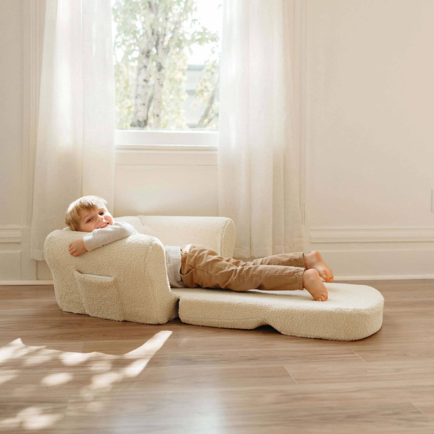 Boy Lying on Tiny Land® Afternoon Couch —— Cream Kids Chair