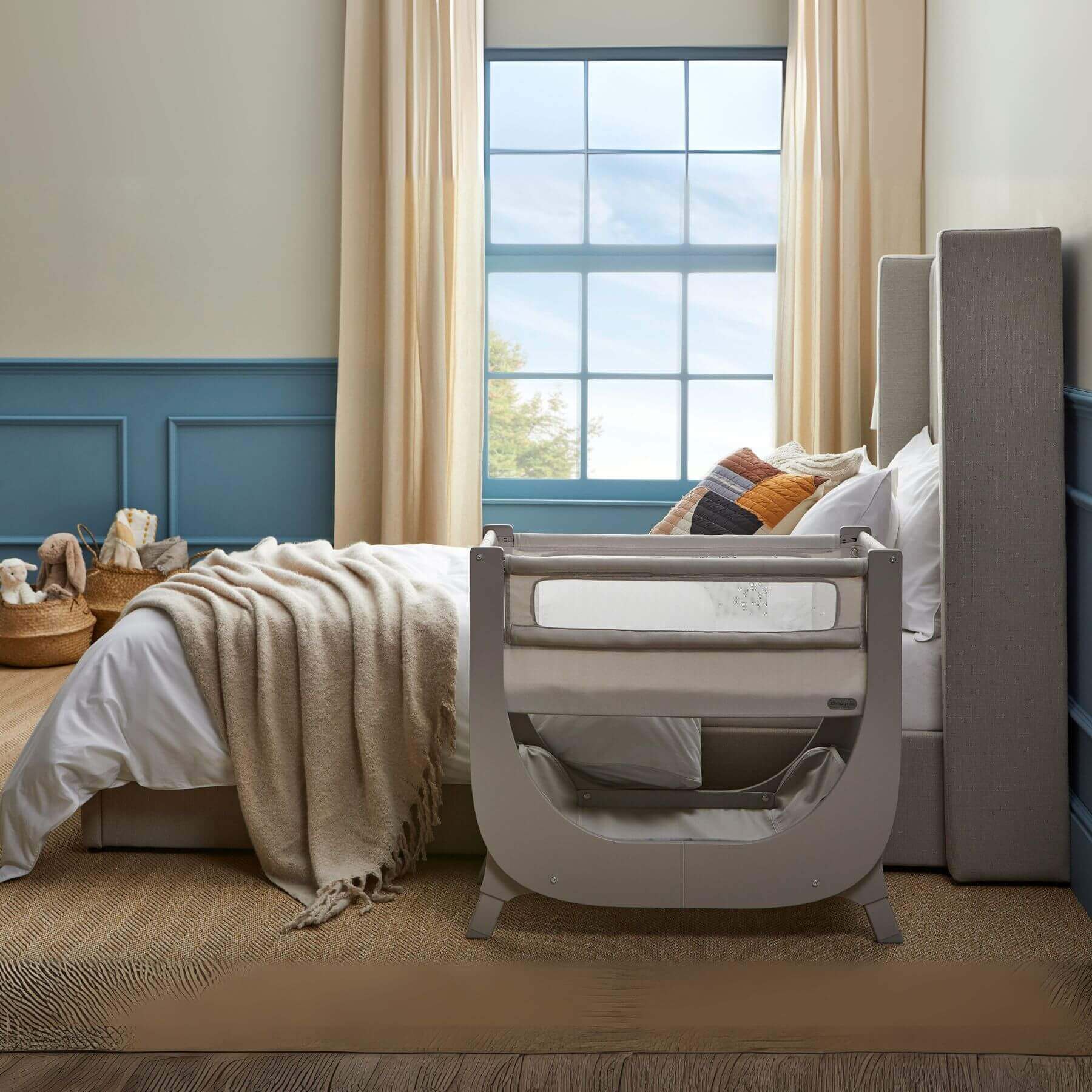 Shnuggle Air Lite Bedside Crib in a bedroom with a window and bed in the background