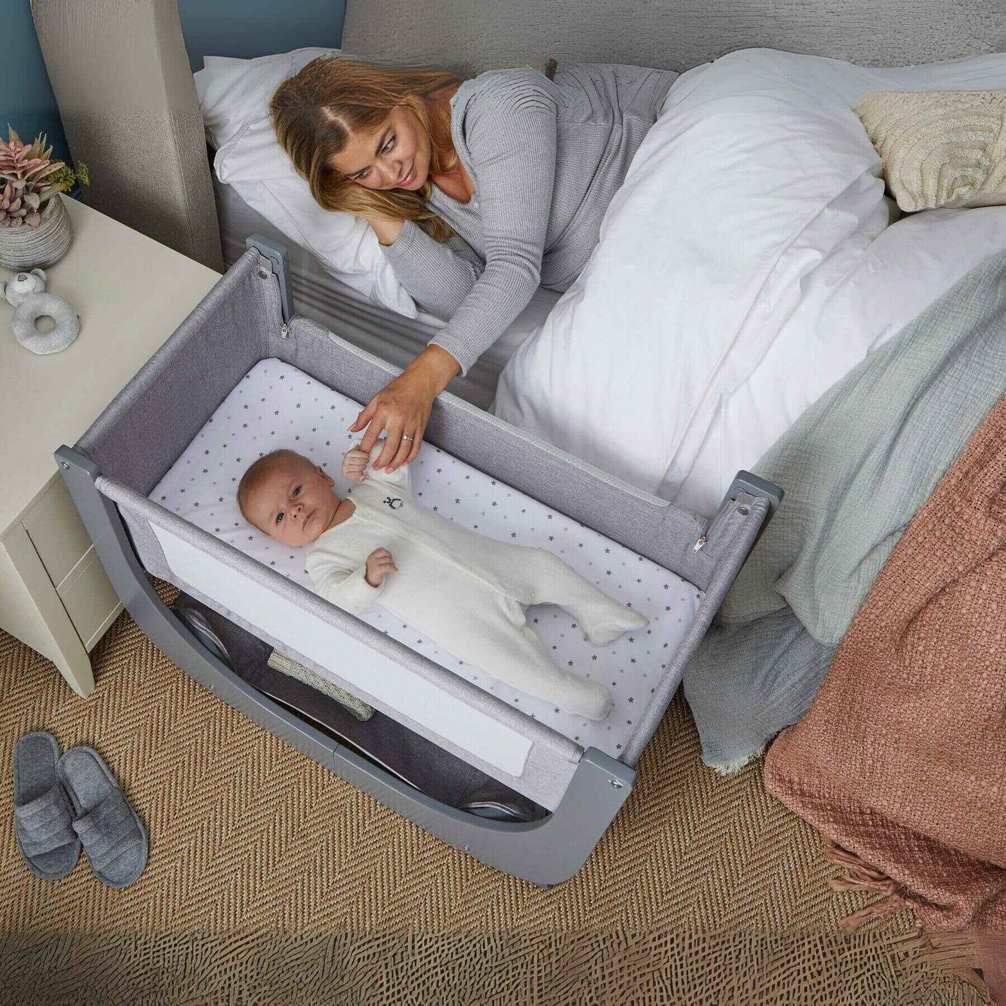 Woman lying in bed with a baby inShnuggle Air Lite Bedside Crib in a bedroom setting.