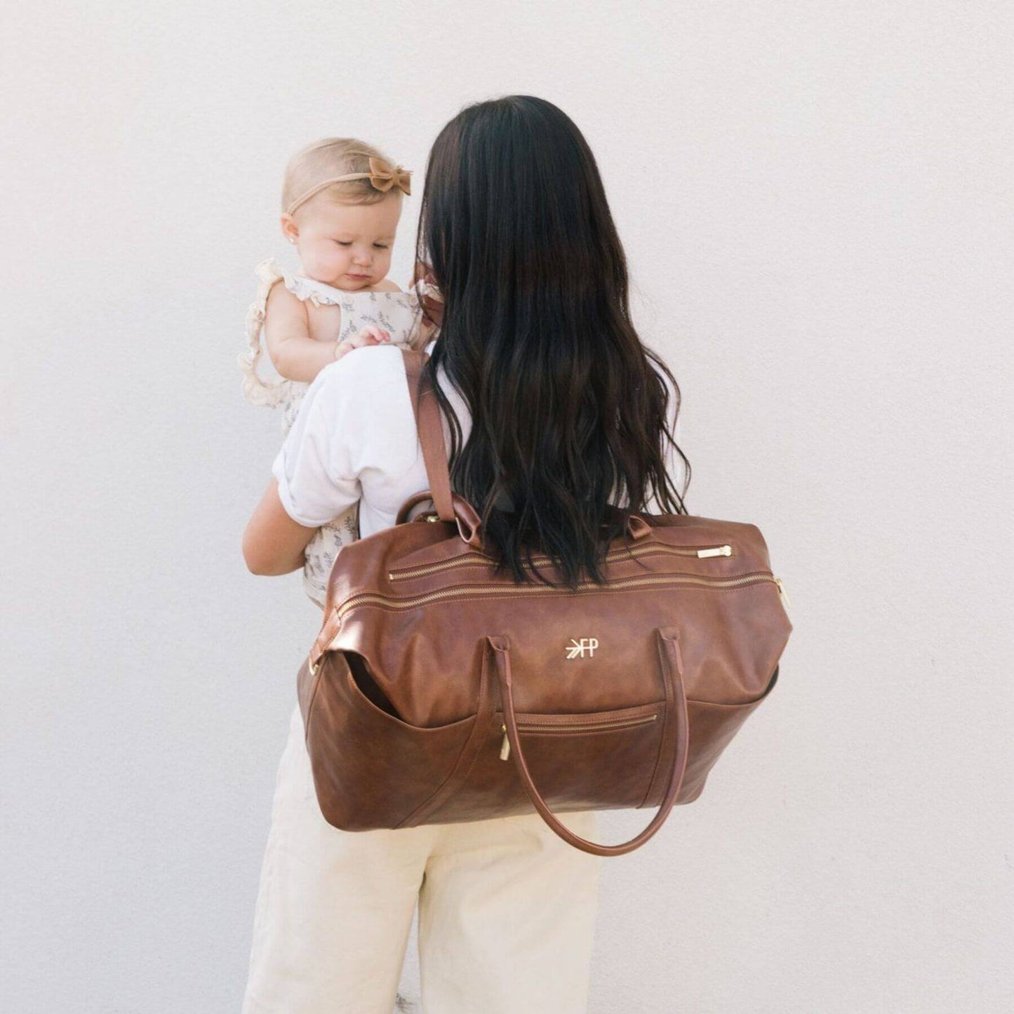 Woman holding a baby and Freshly Picked Amber Minimal Weekender with a visible brand logo