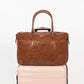 Freshly Picked Amber Minimal Weekender on a light pink suitcase with a visible brand logo