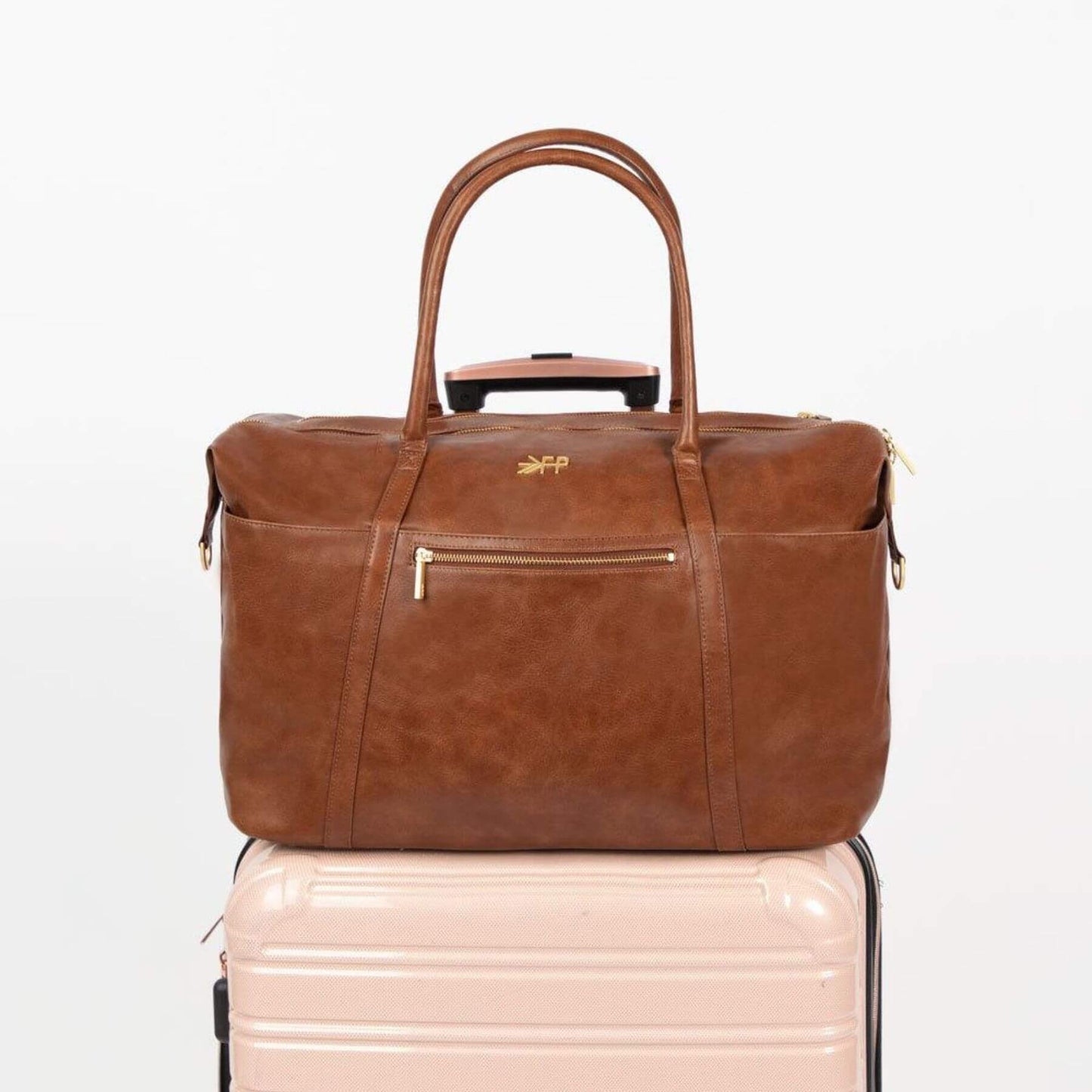 Freshly Picked Amber Minimal Weekender on a light pink suitcase with a visible brand logo