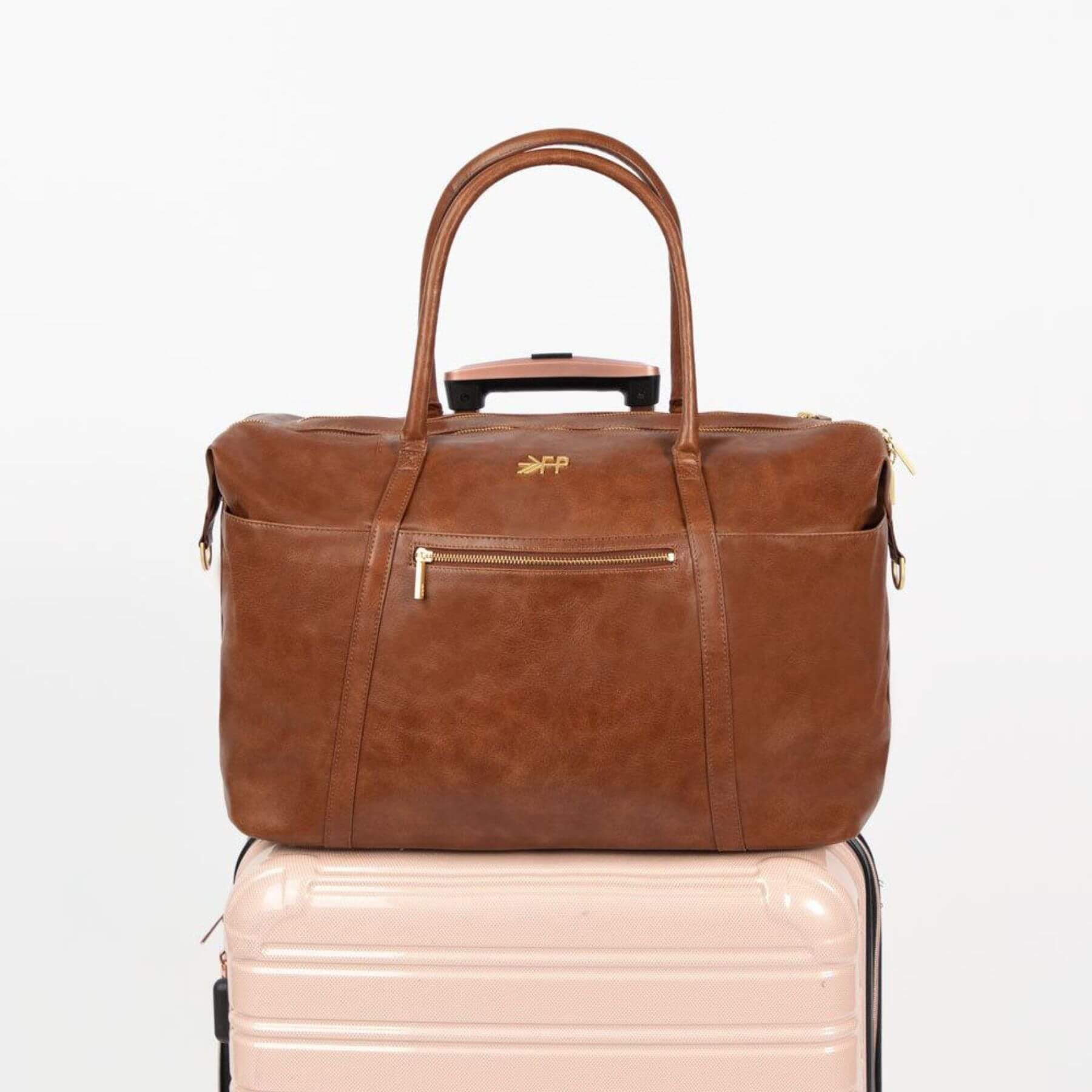 Freshly Picked Amber Minimal Weekender on a light pink suitcase with a visible brand logo