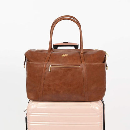 Freshly Picked Amber Minimal Weekender on a light pink suitcase with a visible brand logo