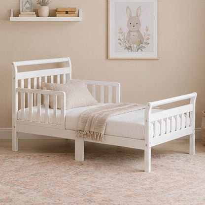 Anna Toddler Bed White in a room with a beige wall and decorative elements.