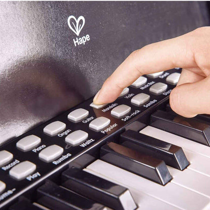 Hand pressing a button on a Hape toy piano