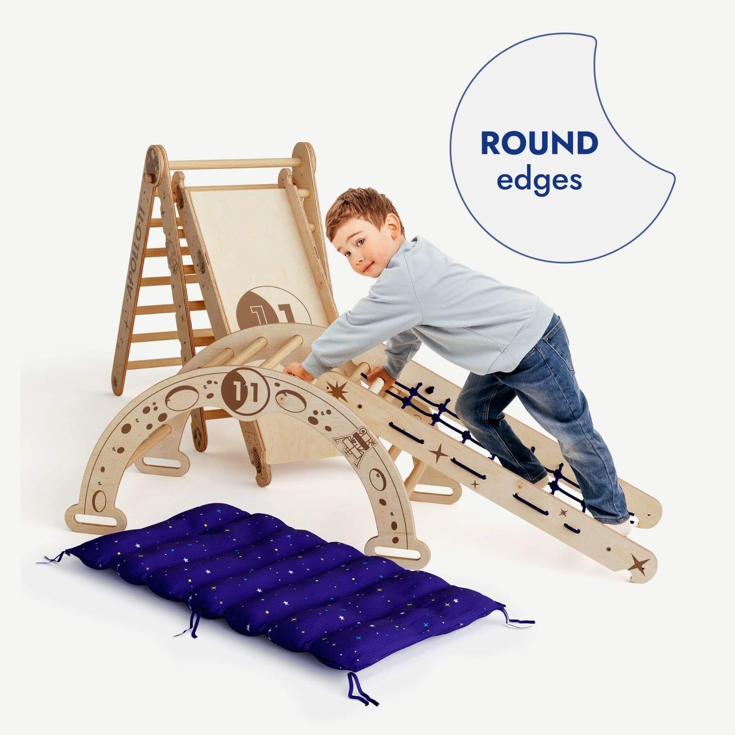 Child playing on a wooden climbing toy with round edges, accompanied by a blue cushion.