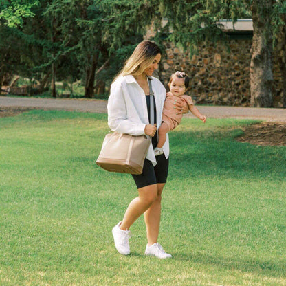 Woman holding a child and Freshly Picked Aspen Seoul Neoprene Tote in a park setting