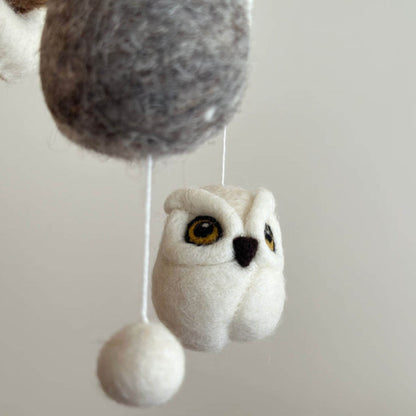 Plush owl toy hanging from a string on a plain background