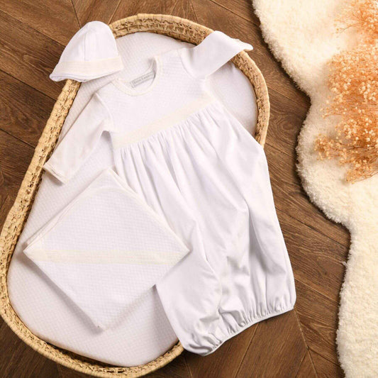 Bebe Sweeny Baby White Quilted Cotton Gown Set (3) in a wicker basket on a wooden floor.