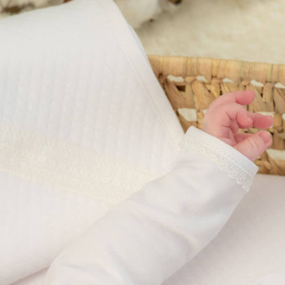 Close-up of a baby's hand in a white sleeve with a blurred background