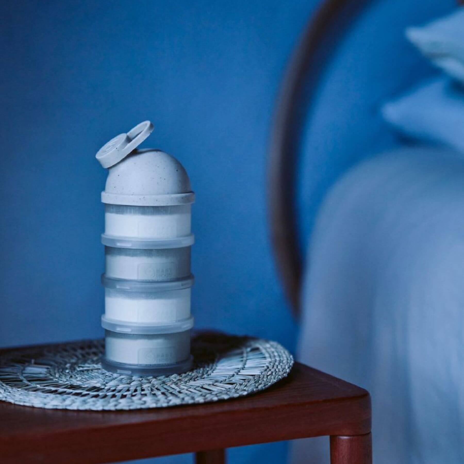 Babydose Formula Dispenser on a wooden table with a blue background