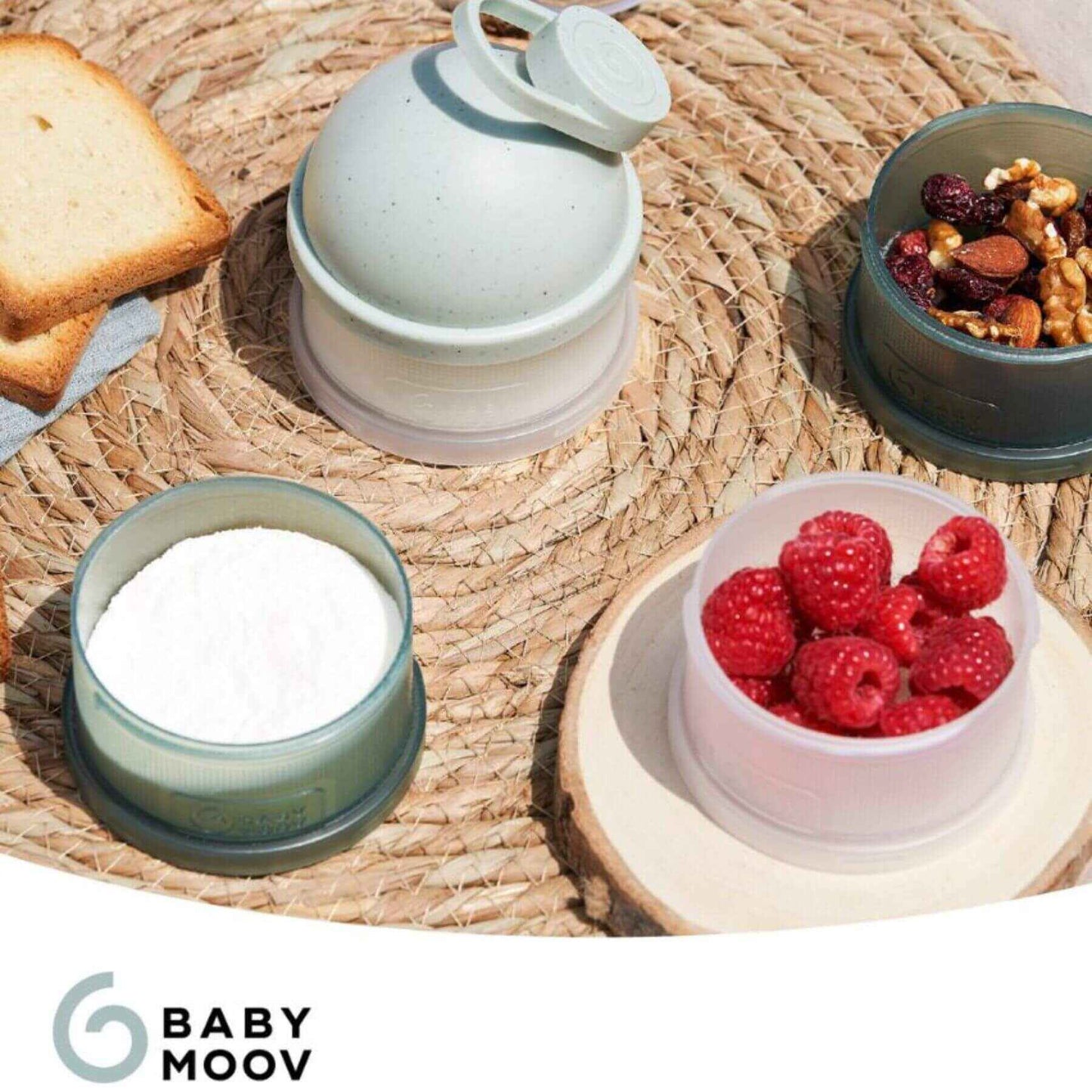 Babydose Formula Dispenser with snacks on a woven mat, featuring the Baby Moov brand.