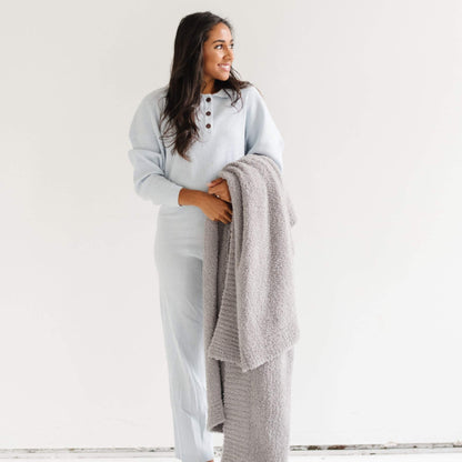 Woman holding Saranoni Bamboni® Throw Blanket in a light gray outfit against a white background
