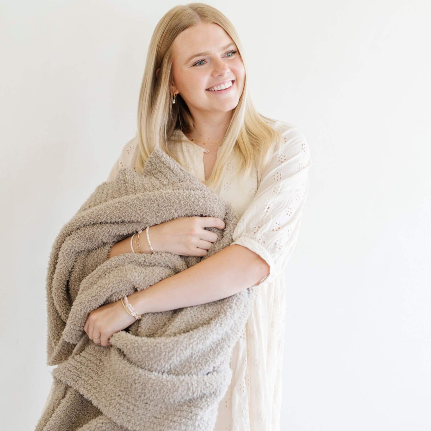 Woman wrapped in Saranoni Bamboni® Throw Blanket against a white background