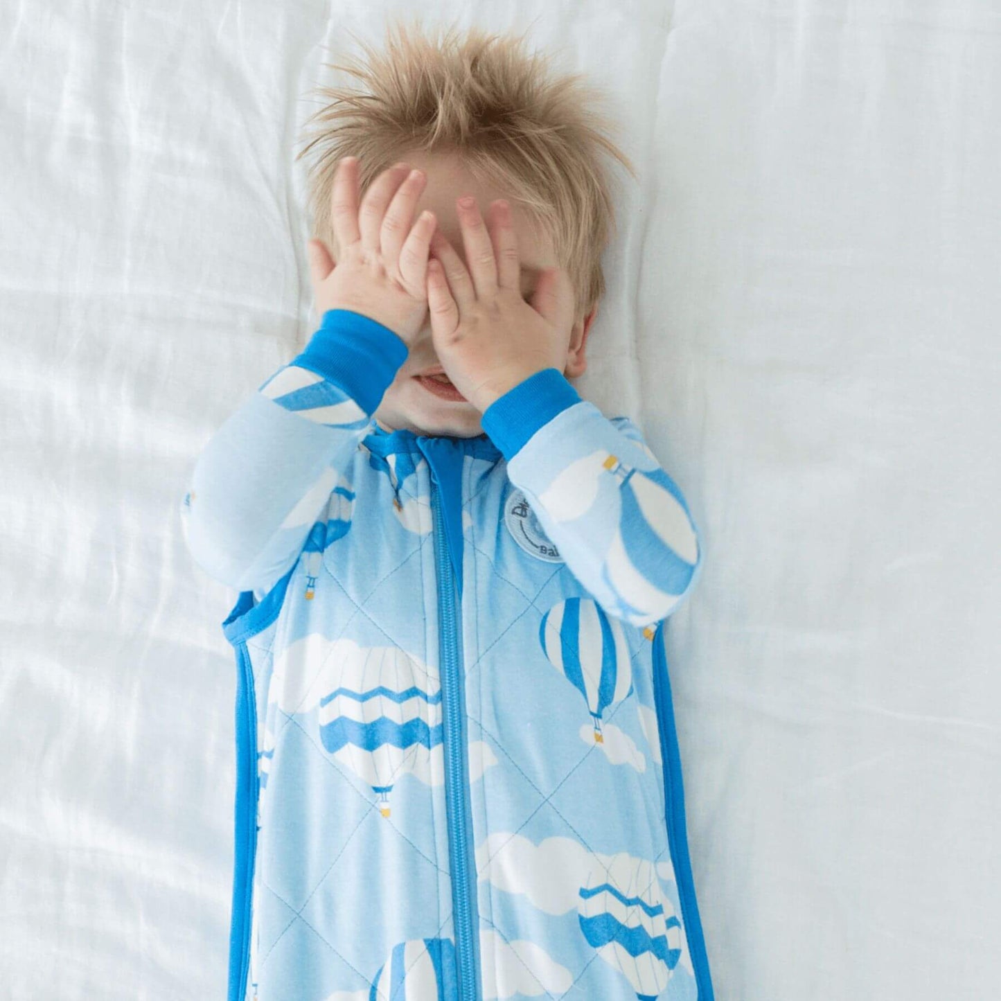 Kid in Bamboo Classic Sleep Sack - Hot Air Ballmoons, lying on bed