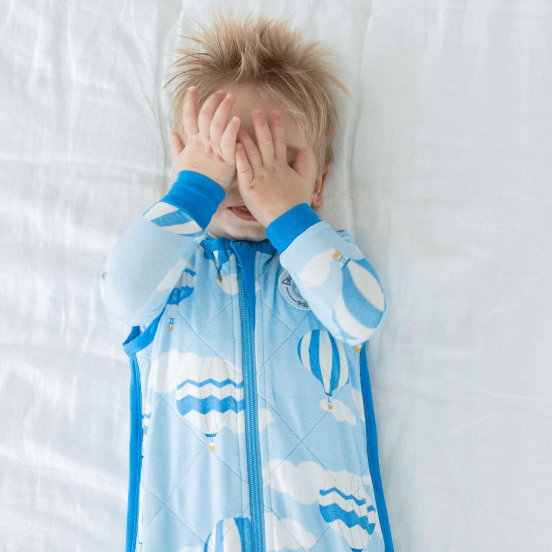 Kid in Bamboo Classic Sleep Sack - Hot Air Ballmoons, lying on bed