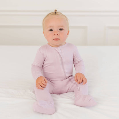 Baby wearing Dreamland Baby Bamboo Pajamas w/ DreamCuffs® - Blush sitting on a white surface