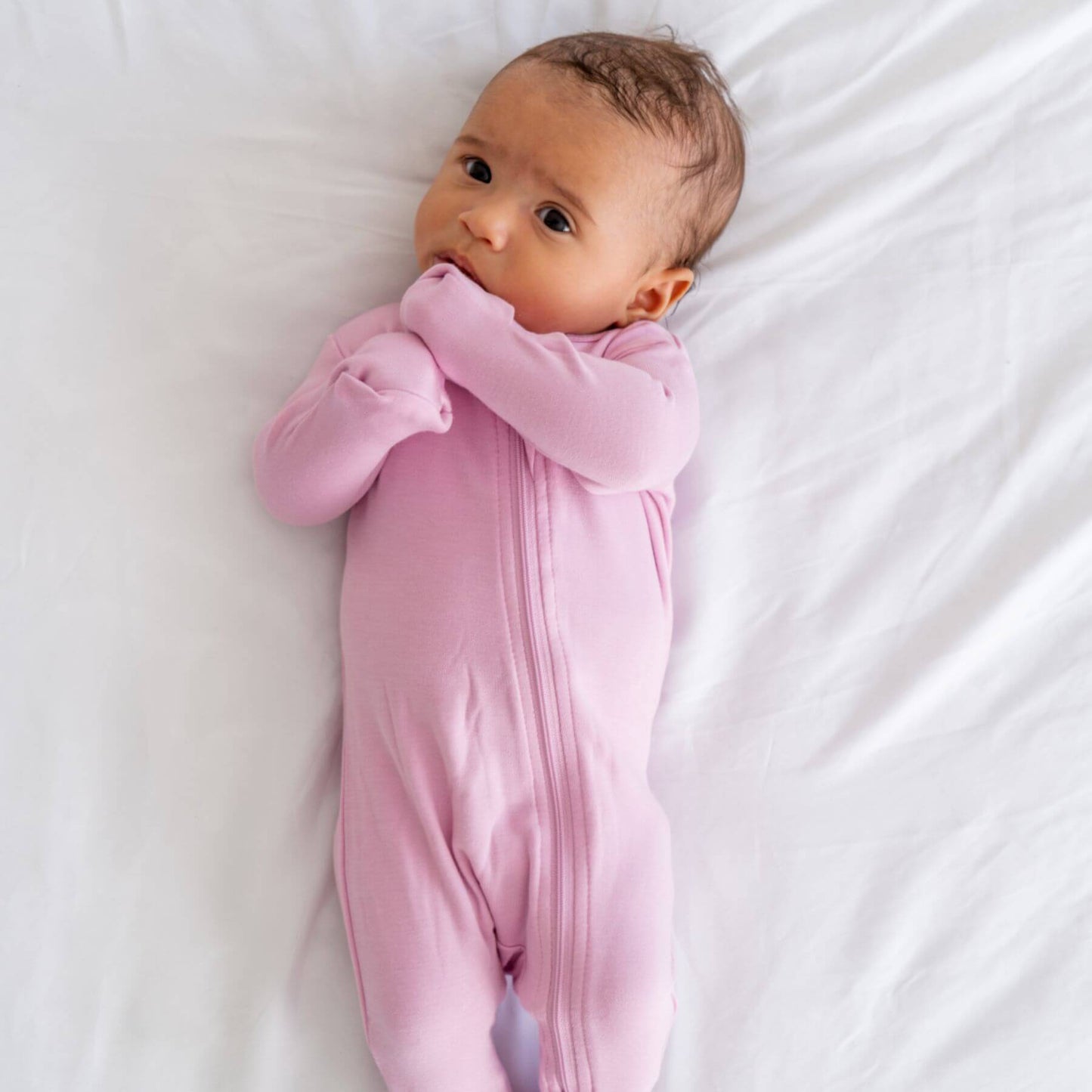 Baby in Dreamland Baby Bamboo Pajamas w/ DreamCuffs® - Mauve lying on a white surface