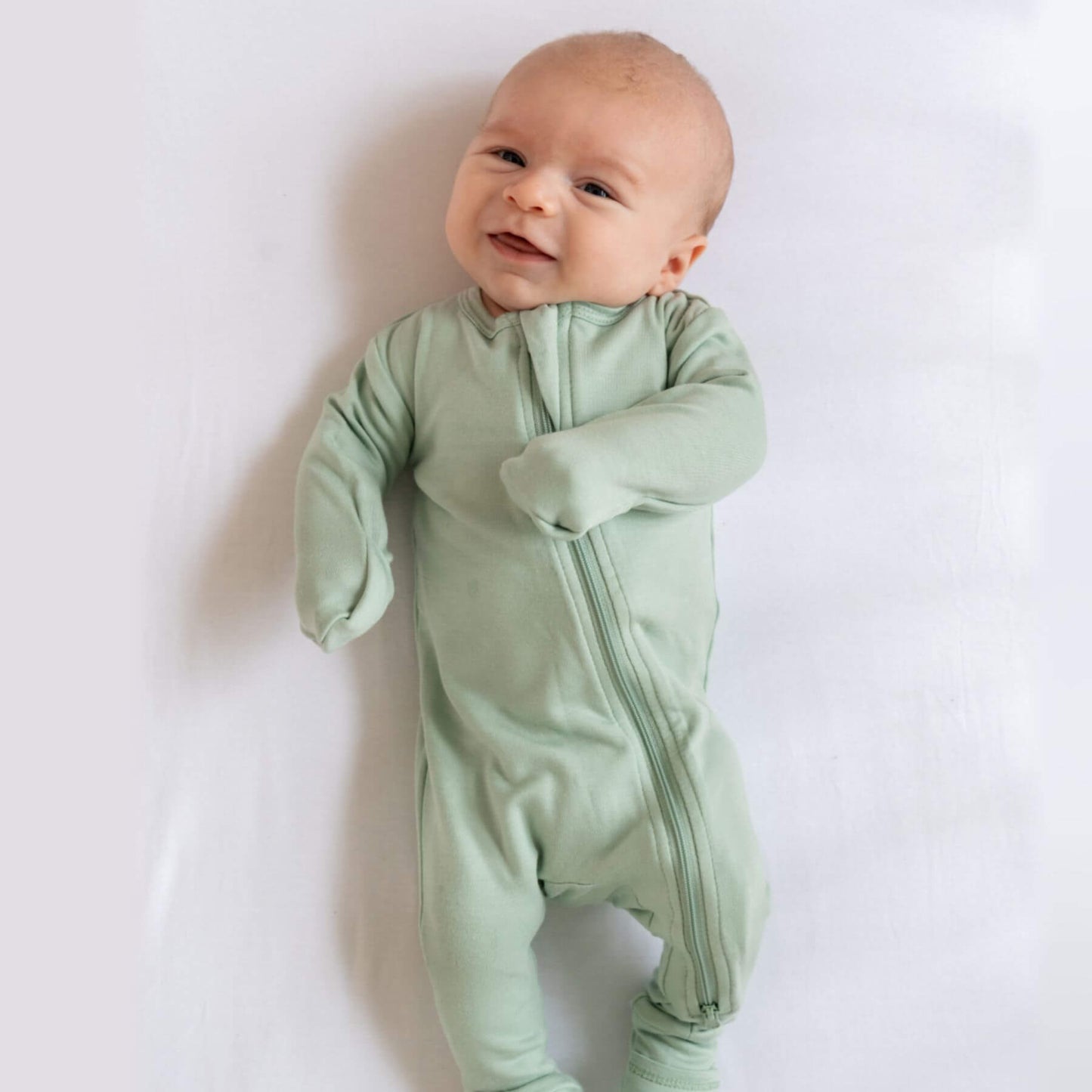 Baby wearing Dreamland Baby Bamboo Pajamas w/ DreamCuffs® - Sage on a white background