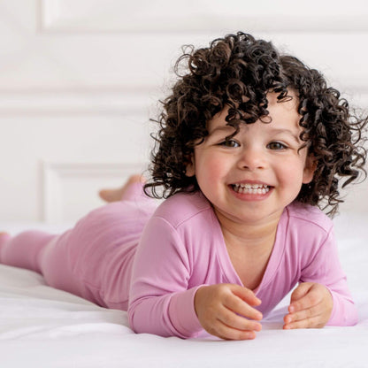 Kid lying on bed, wearing Dreamland Baby Toddler/Kids Bamboo Pajamas - Misty Mauve