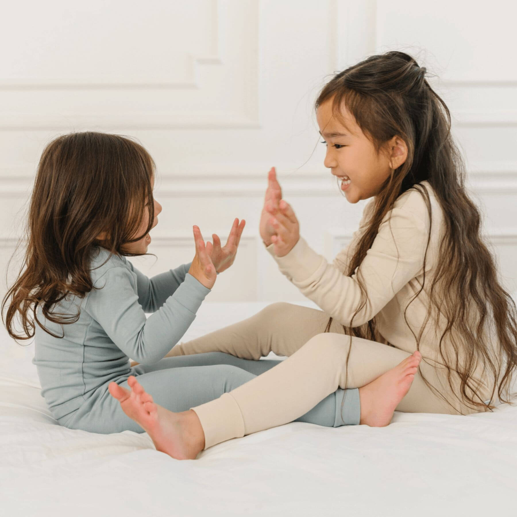 Two girls in Dreamland Baby Toddler/Kids Bamboo Pajamas, sitting on bed
