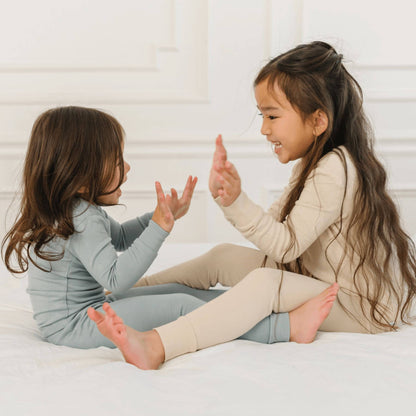 Two girls in Dreamland Baby Toddler/Kids Bamboo Pajamas, sitting on bed