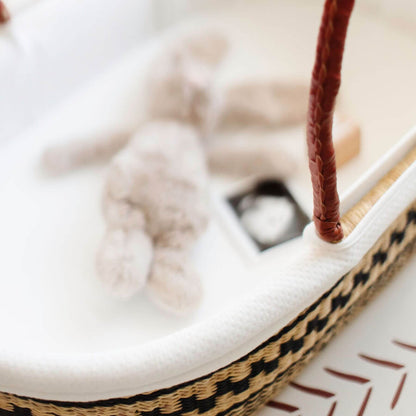 Close-up of a woven basket with a white cushion and a brown handle.