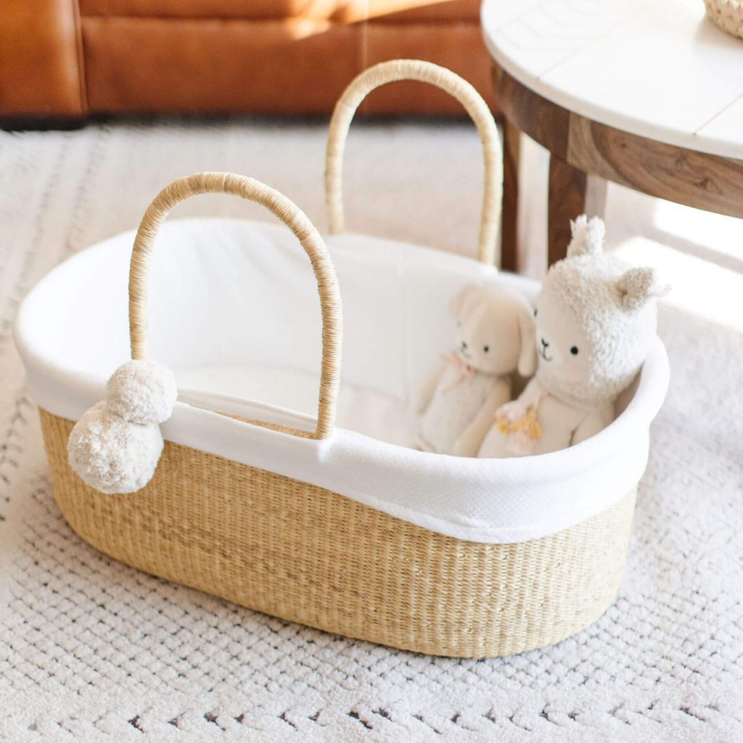Woven baby basket with white interior containing plush toys on a textured surface.