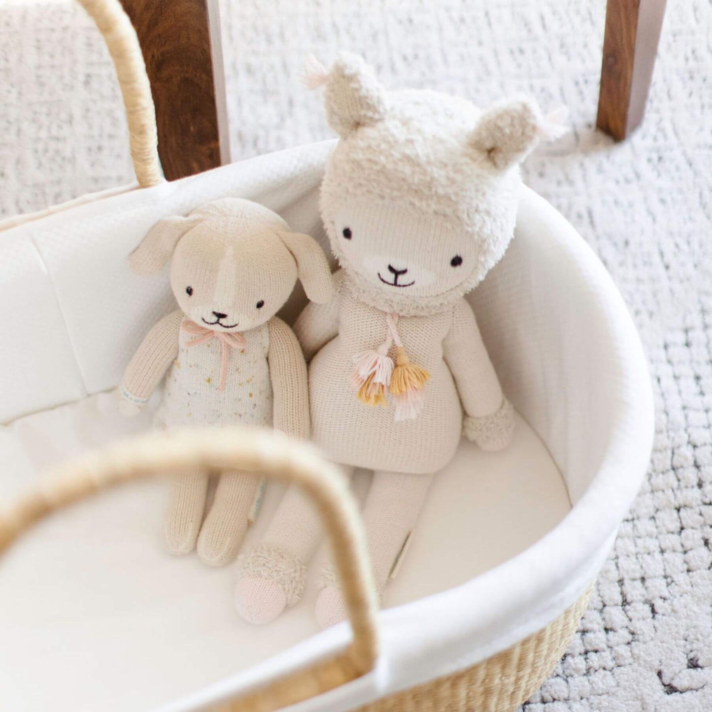 Two plush toys, a rabbit and a bear, sitting in a white basket on a textured surface.