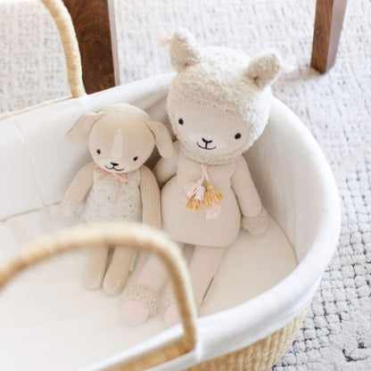 Two plush toys, a rabbit and a bear, sitting in a white basket on a textured surface.