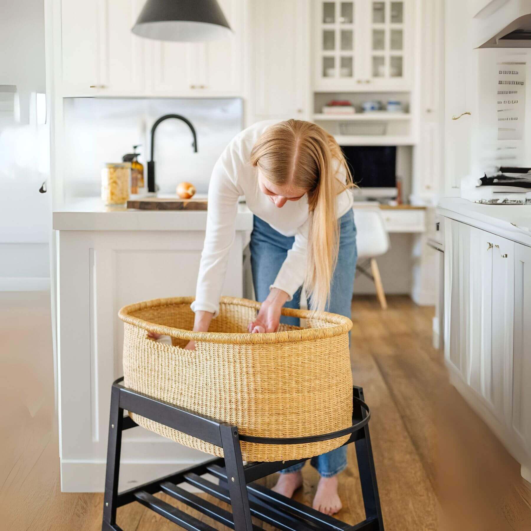 Woman arranging African Moses Basket No Hood Inset Handle on a stand in a kitchen.