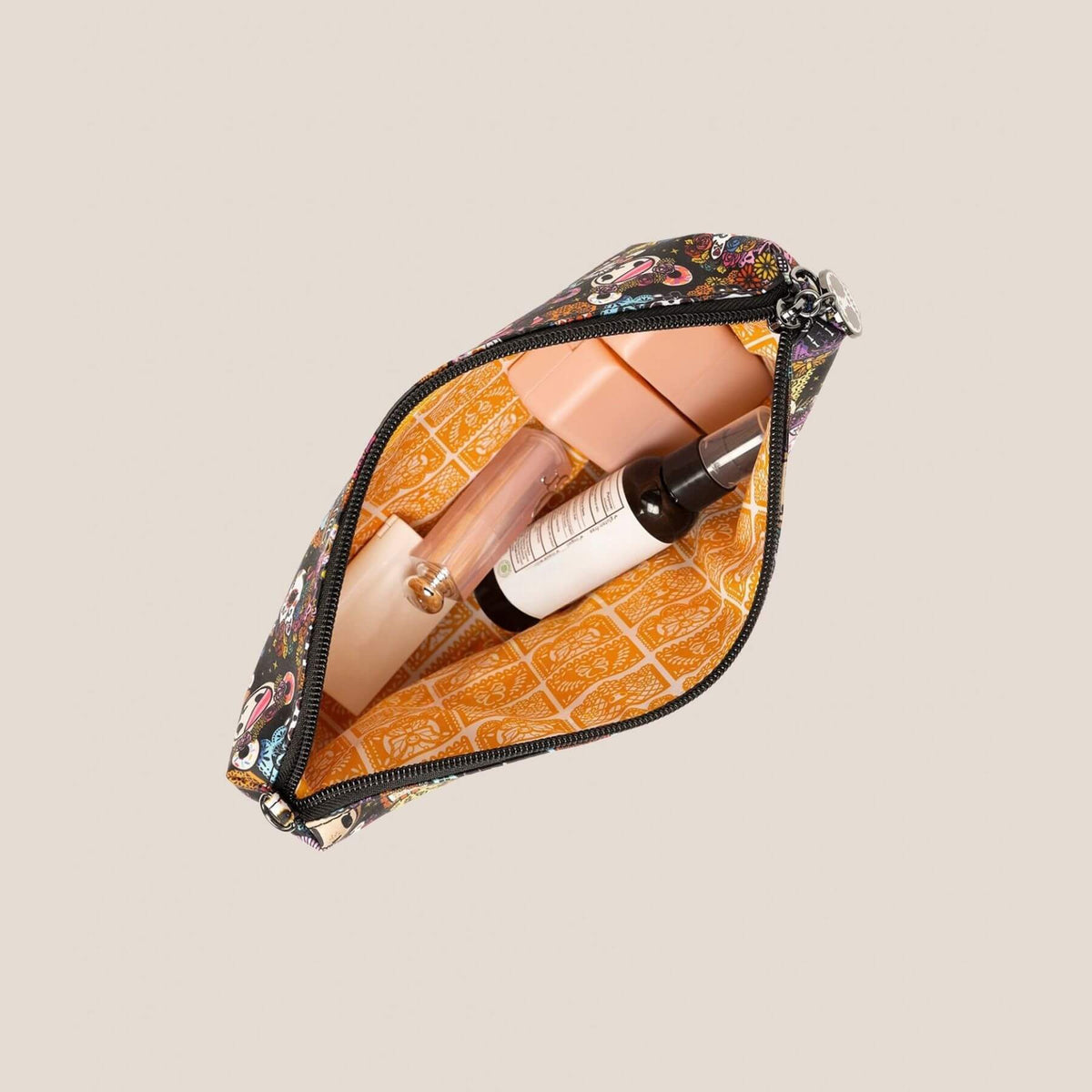 tokidoki Be Quick Crossbody Diaper Bag Accessory – Dia de los Muertos, shown open to reveal makeup items inside, including a beige tube, a white and black bottle, and a peach-colored item.