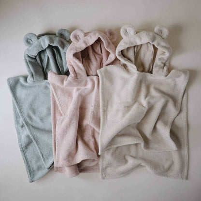 Mushie Bear Poncho Towels in different colors arranged on a light background