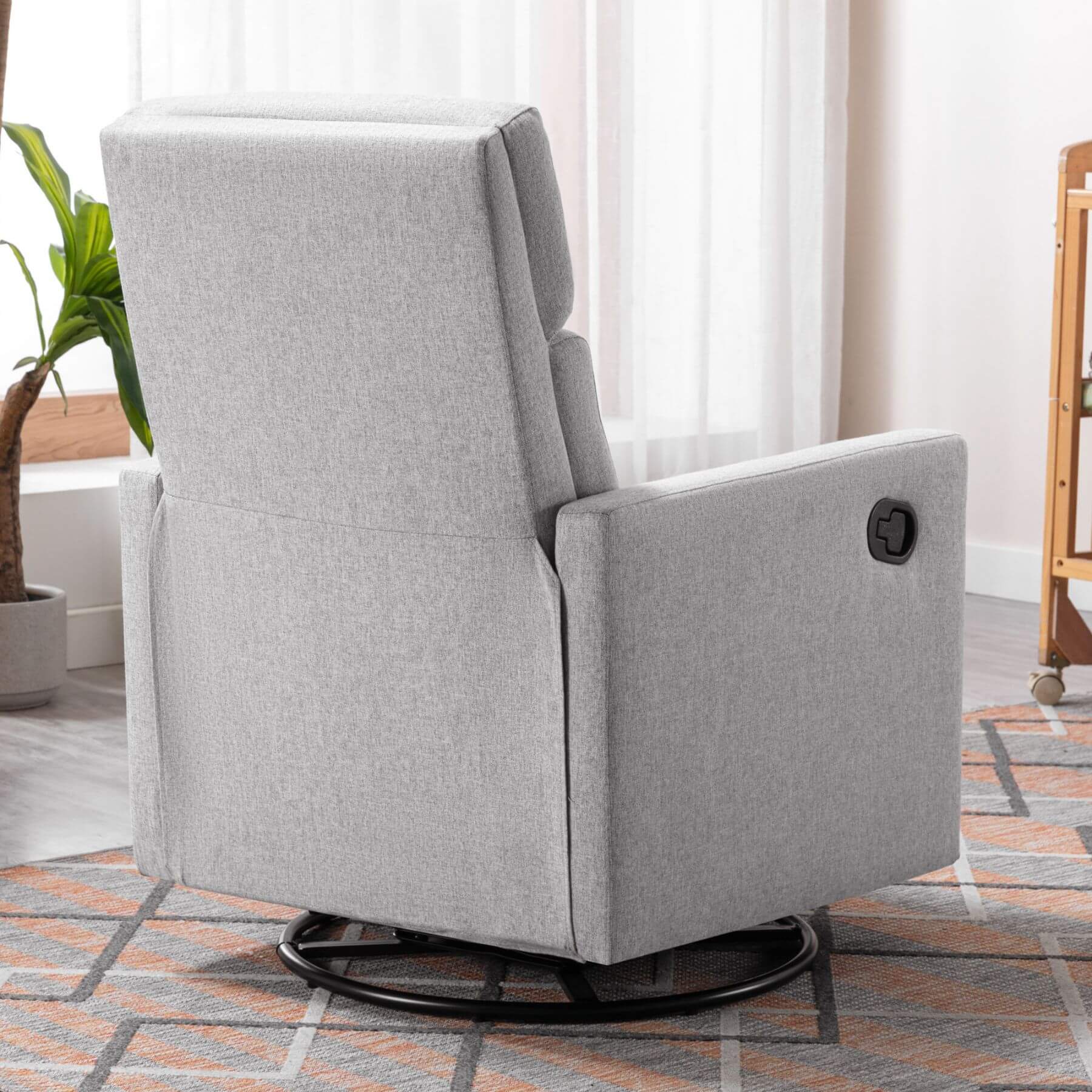 Gray recliner chair in a room with a plant and window blinds.