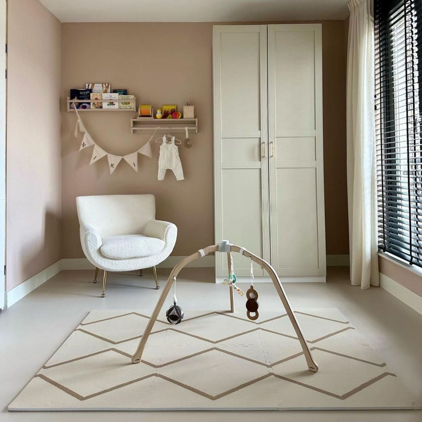 Nursery room with a white armchair, wardrobe, and baby play gym on Eeveve Beni Autumn Gold Play Mat