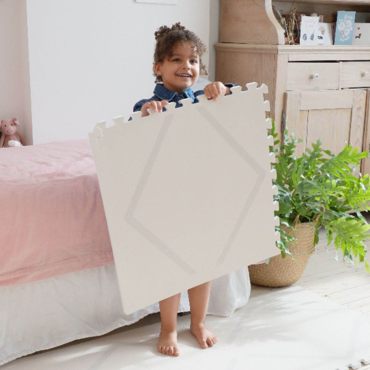 Child holding Eeveve Beni Cashmere Play Mat in a bedroom setting