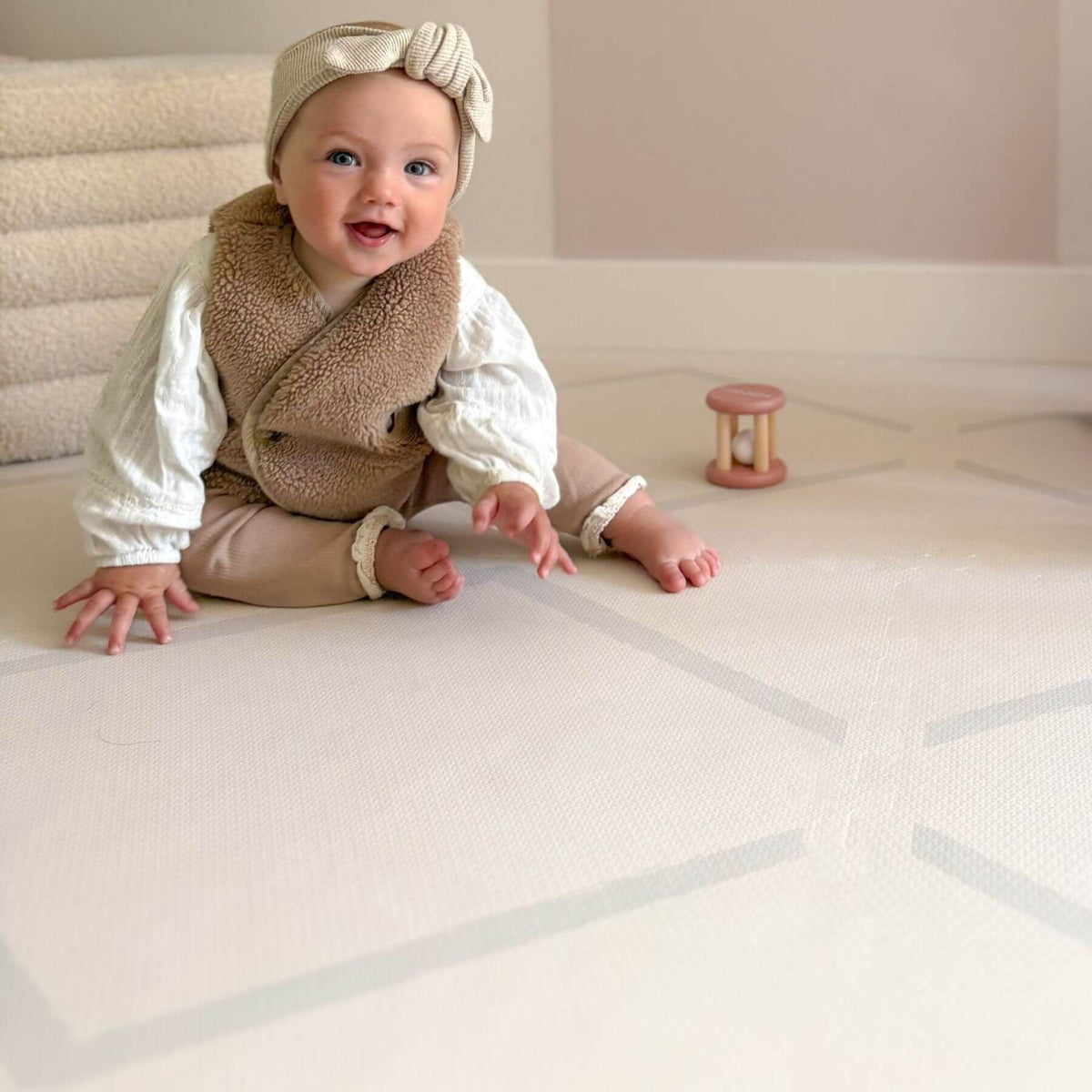 Baby in a brown vest and white outfit on Eeveve Beni Cashmere Play Mat